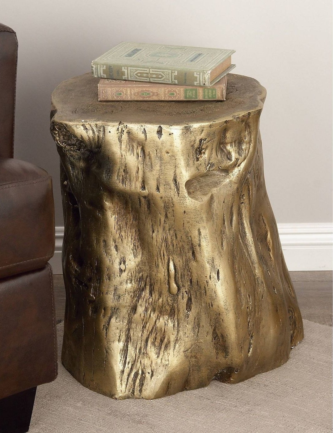 The gold-colored tree-trunk-looking side table with books on it