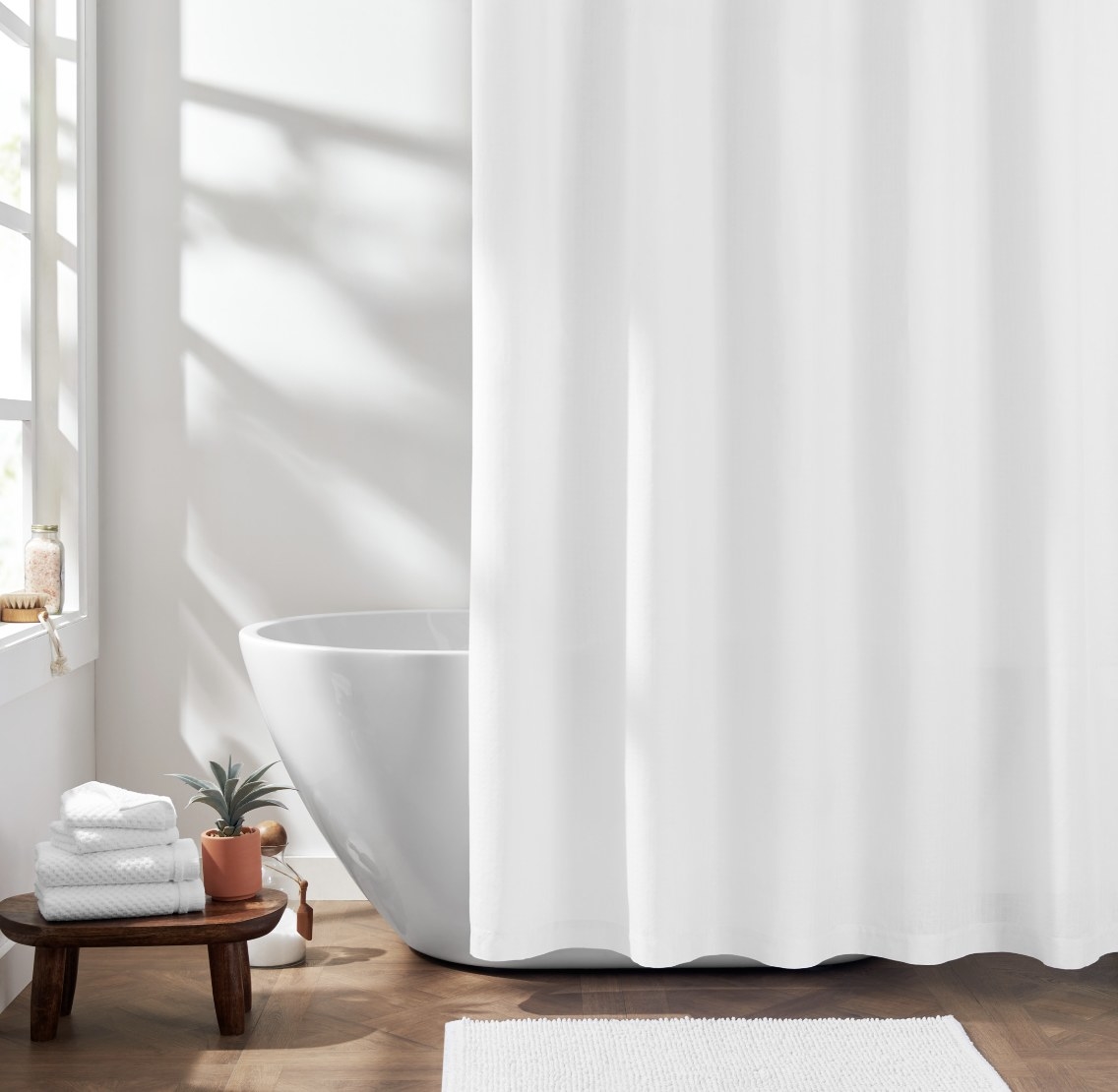 The white curtain is in a natural and bright bathroom