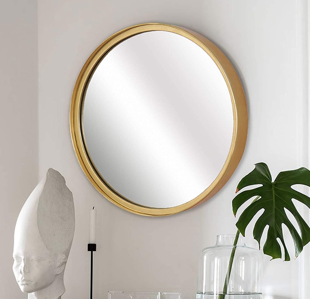 A round mirror with a gold frame mounted on a wall