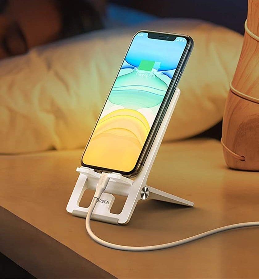 The phone mount on a bedside table with a phone on it