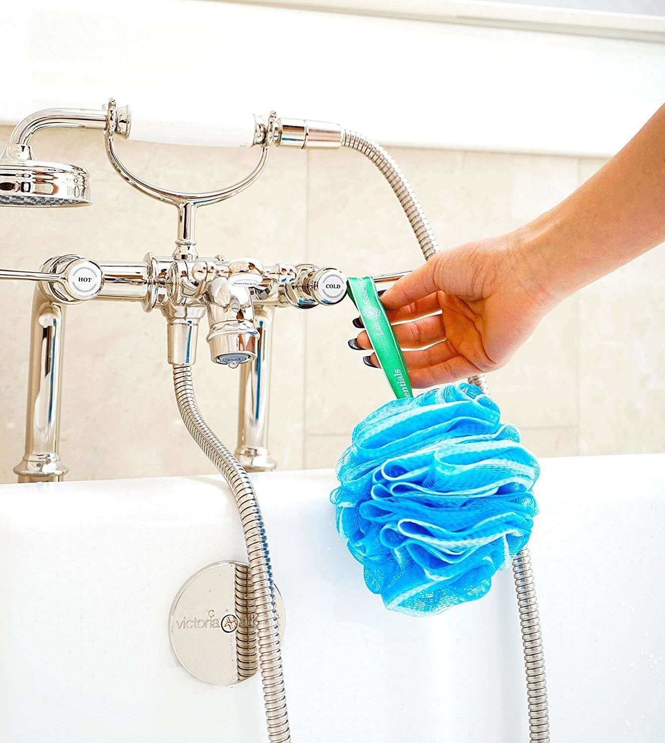 A person hanging a loofah on their faucet