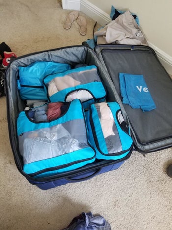 same packing cubes neatly stacked in a blue suitcase
