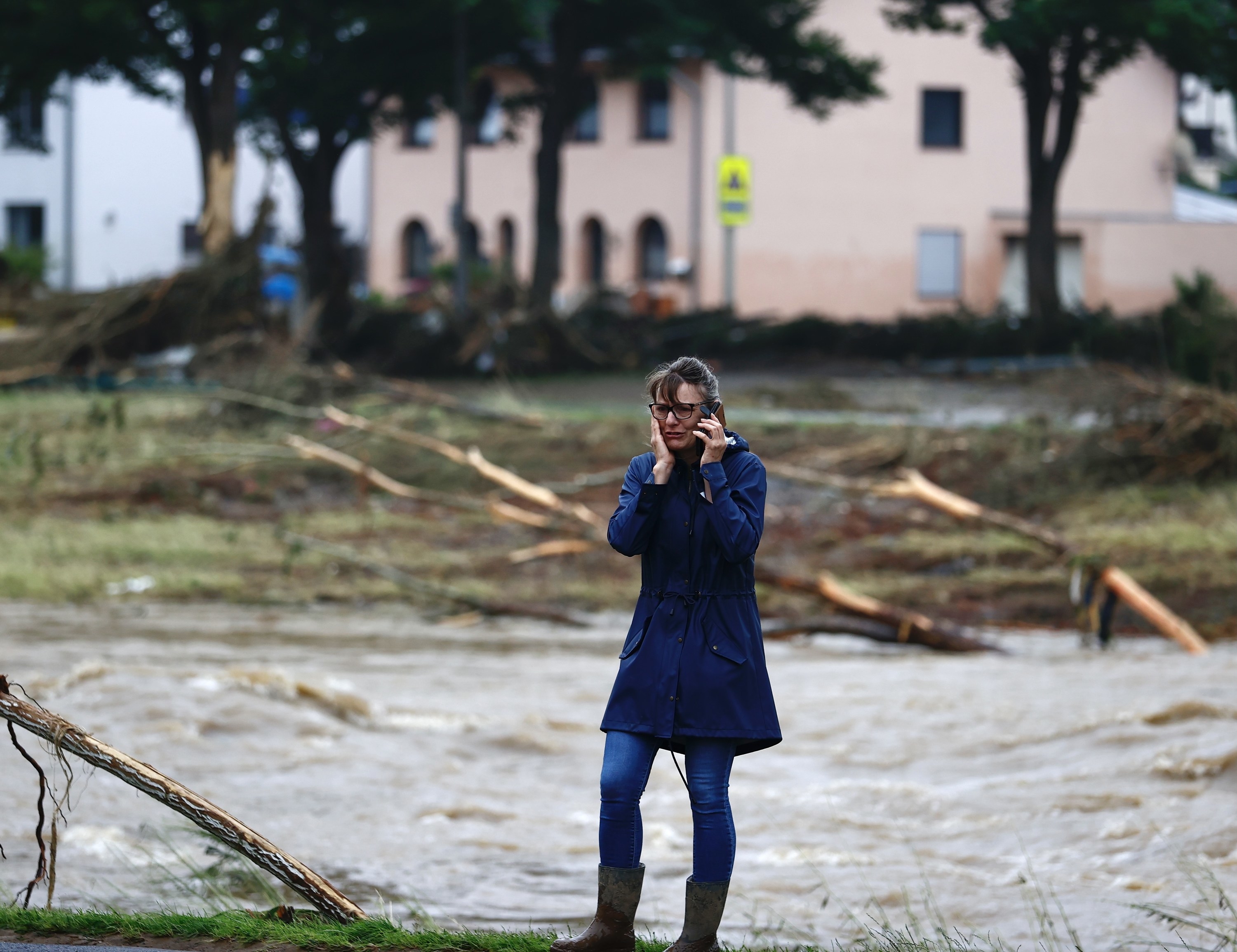 A woman on the phone looking worried with floodwaters in the background