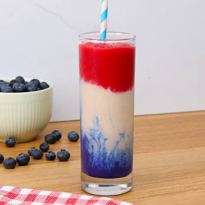 A glass with layers of red white and blue smoothie.