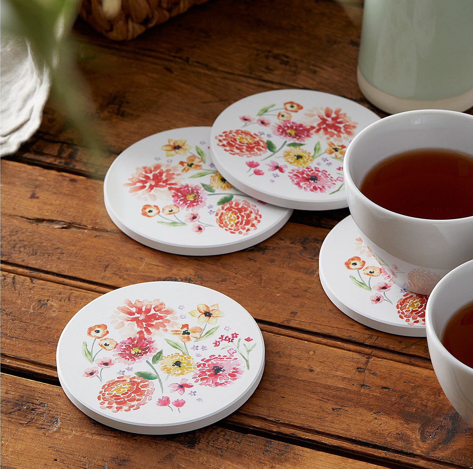 floral coasters on a wooden table next to cups of tea