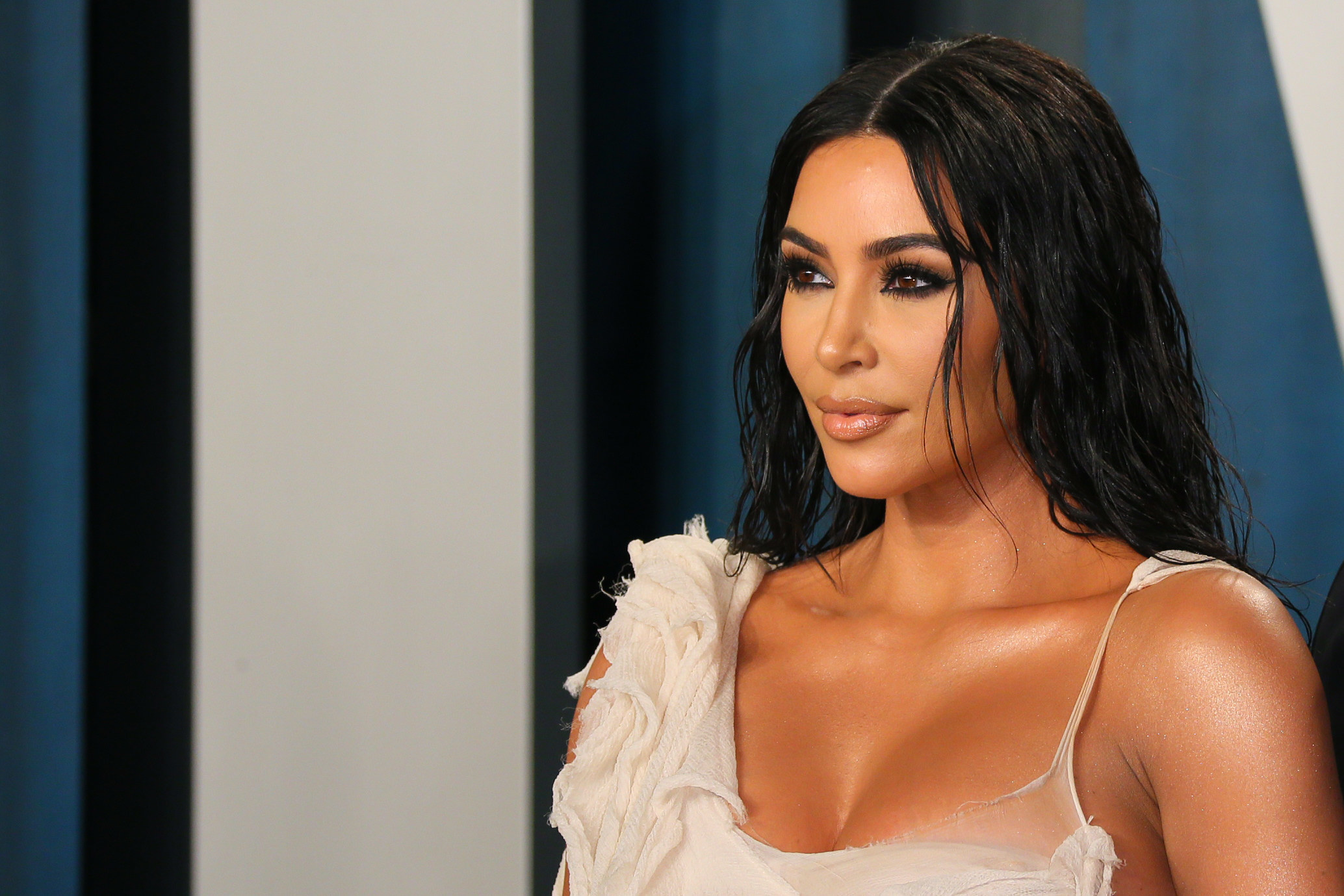 Kim Kardashian in an off-white dress looking at someone off-camera