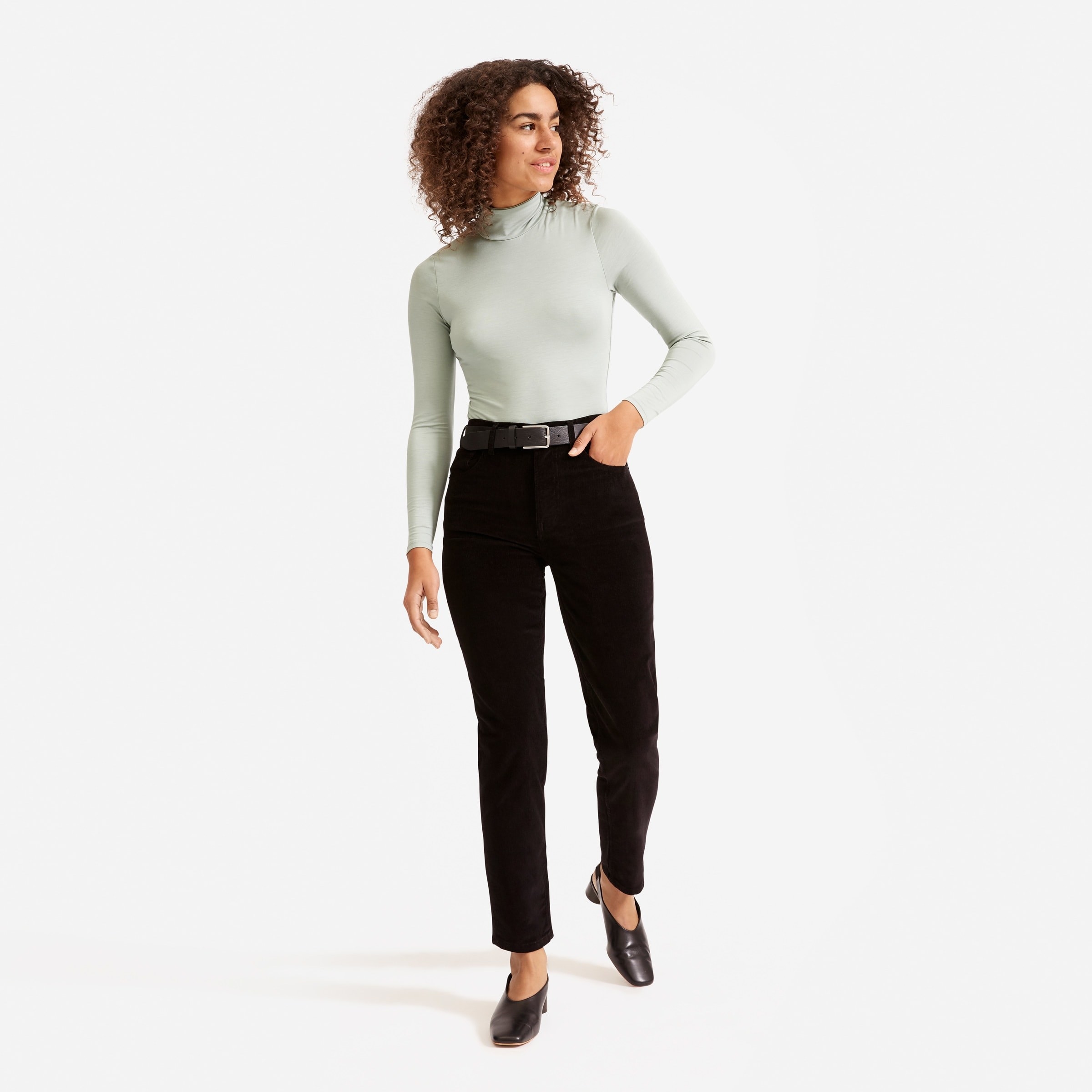 a model in a green turtleneck and black corduroy pants