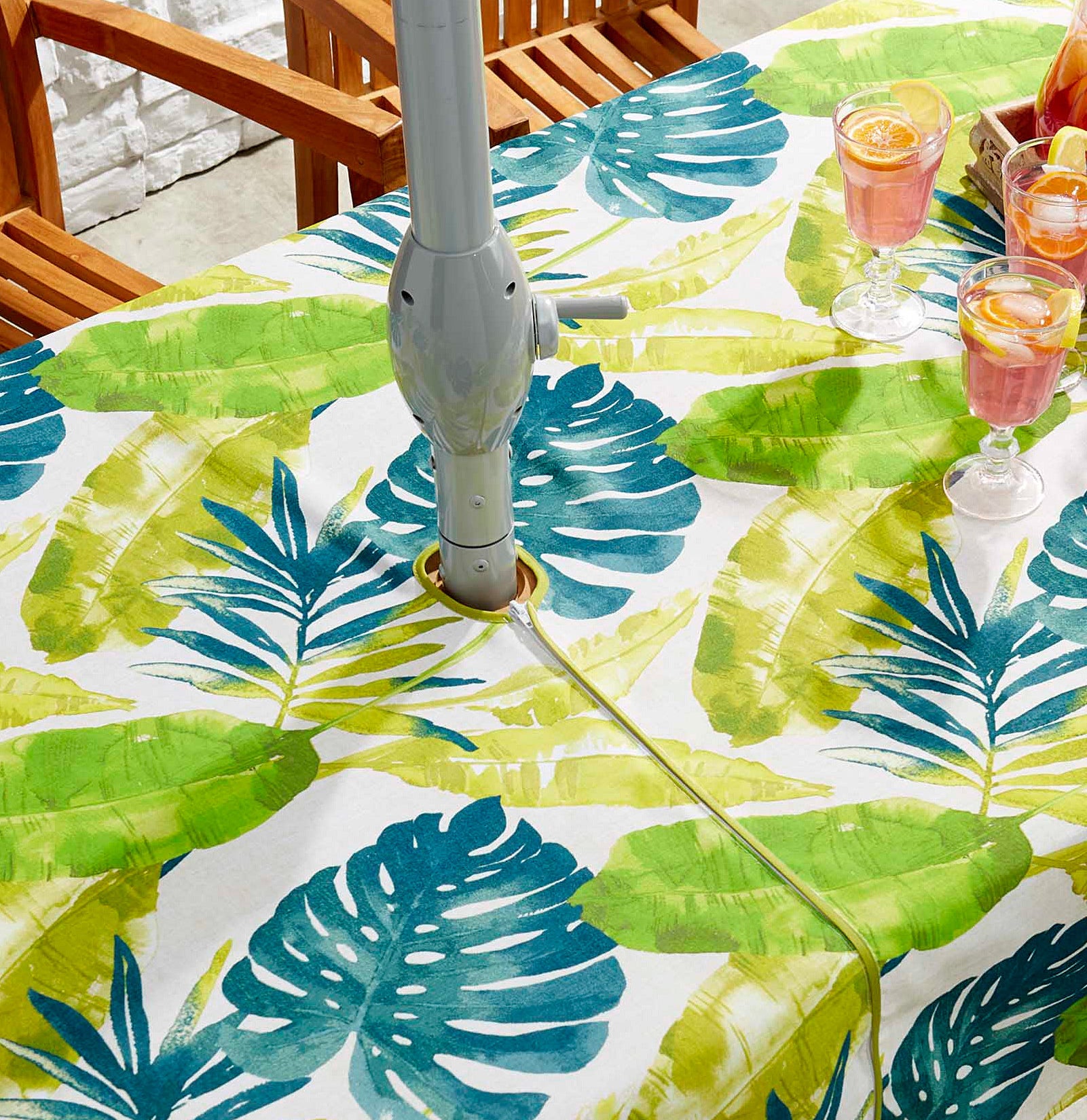 a botanical patterned table cloth on a patio table with a hole for the umbrella