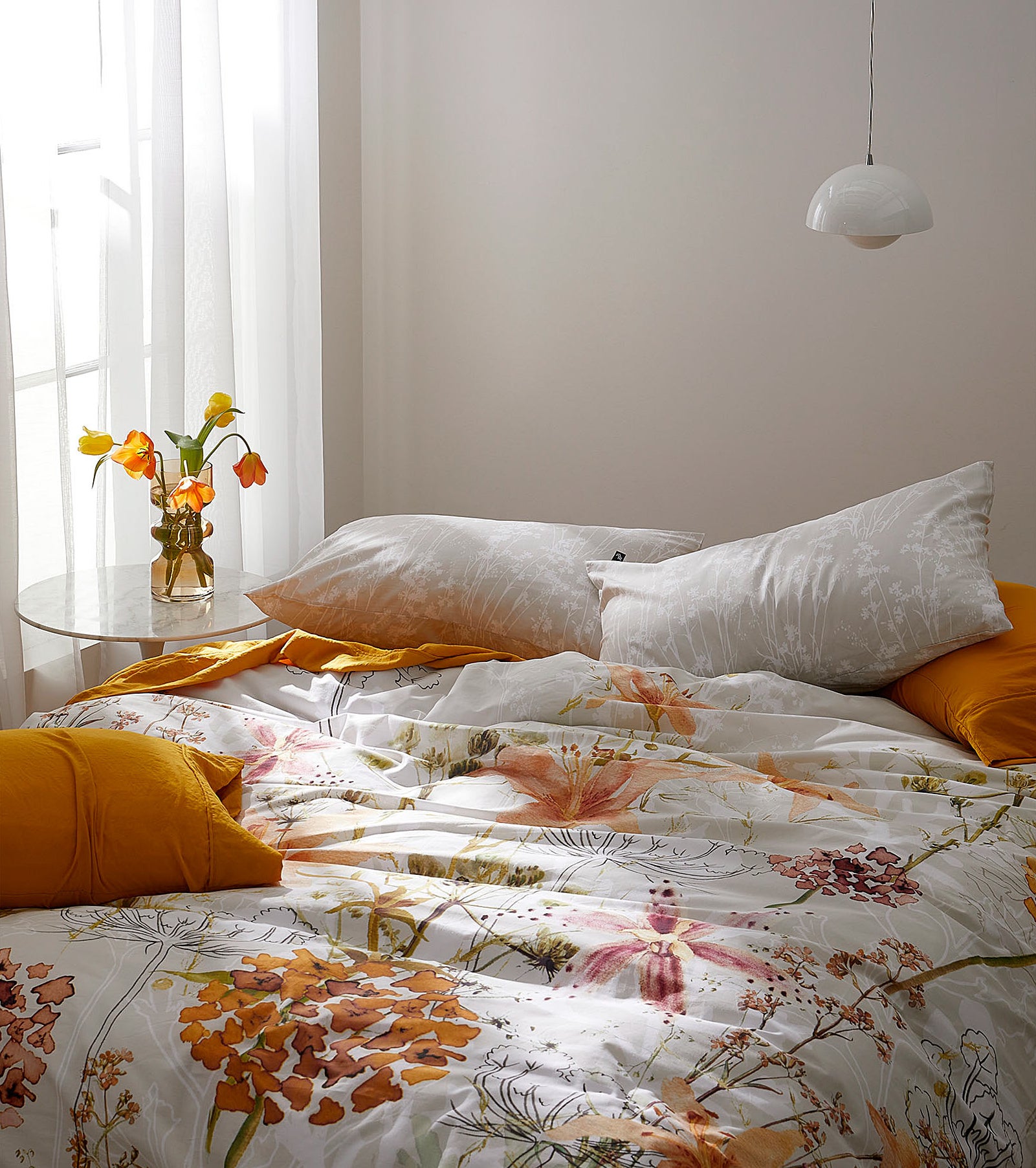 a cozy bed covered in warm colours and florals