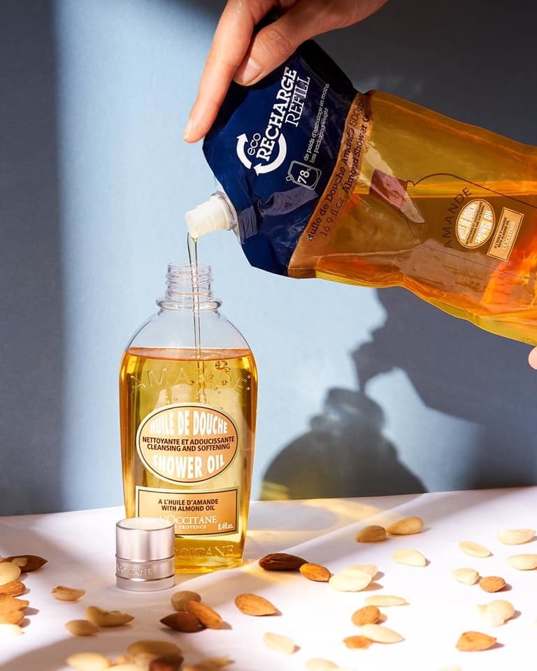 A bottle of L&#x27;Occitane almond shower oil being refilled.