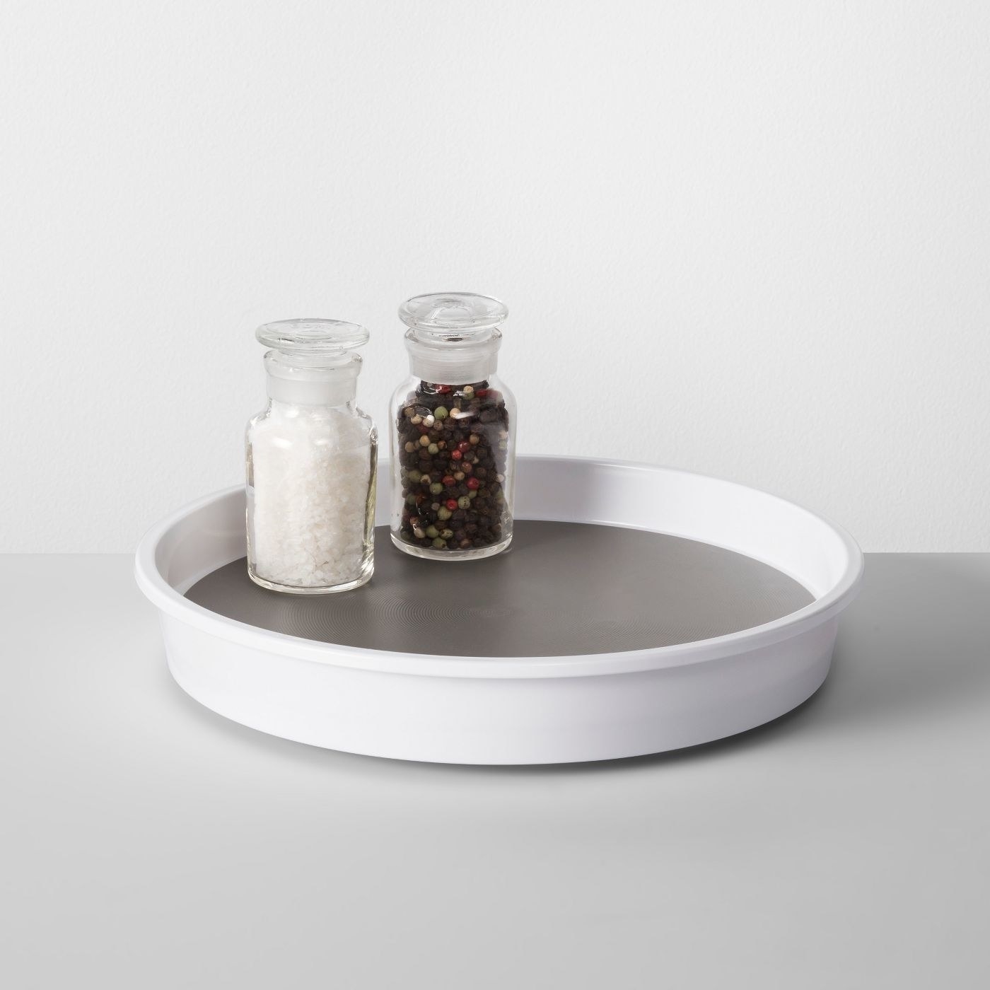 A white kitchen cabinet turntable with salt and pepper shaker on it