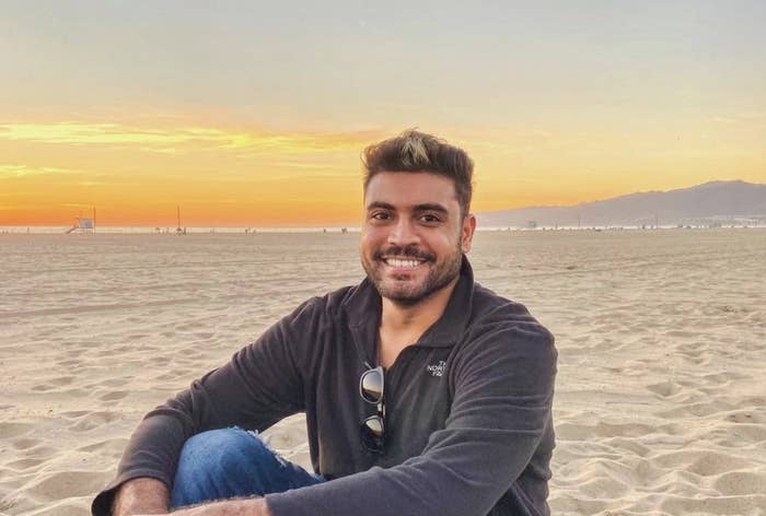 Mat sitting on the sand on a beach and smiling