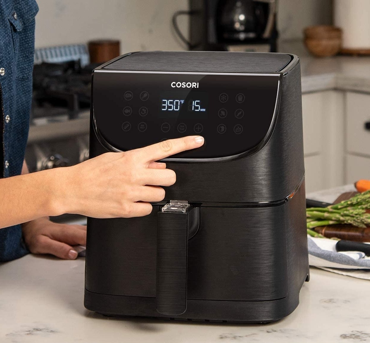 A person pressing a button on the face of the air fryer