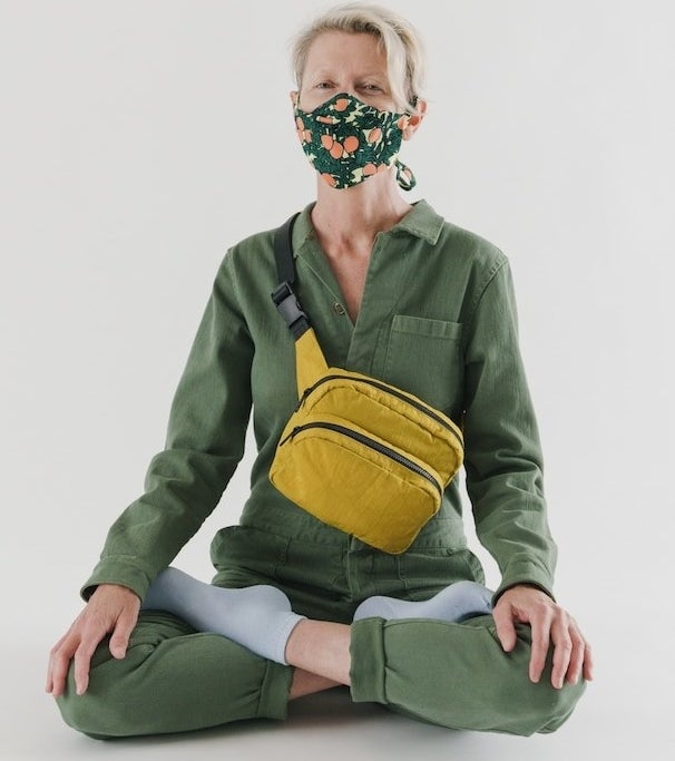 a person sitting cross legged wearing a mask and the large fanny pack