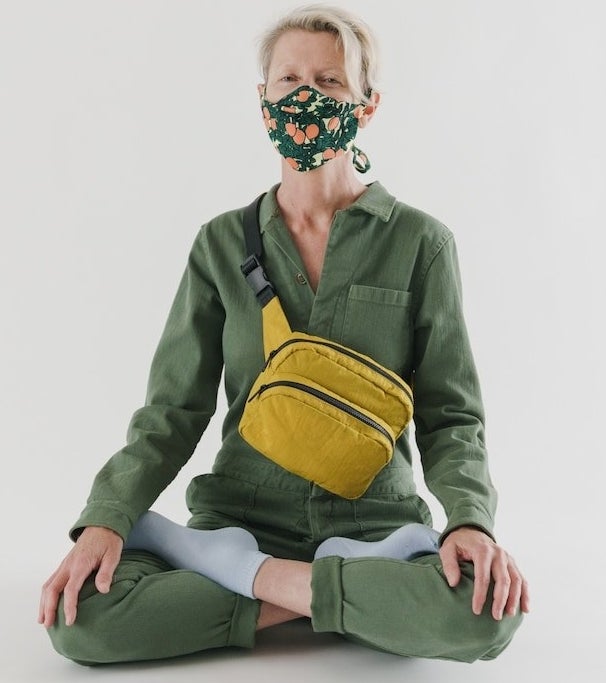 a person sitting cross legged wearing a mask and the large fanny pack