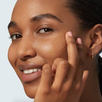 Black model applying sunscreen and appears clear on skin