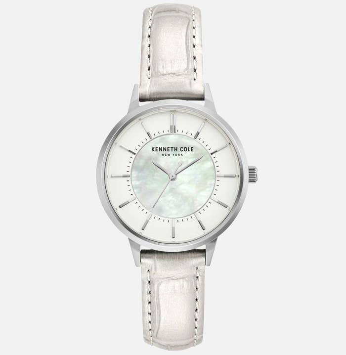 A white, metallic leather watch with a mother of pearl dial face with "KENNETH COLE NEW YORK" written on face