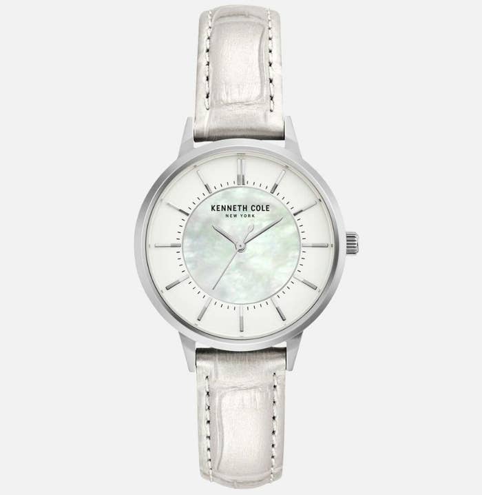 A white, metallic leather watch with a mother of pearl dial face with &quot;KENNETH COLE NEW YORK&quot; written on face