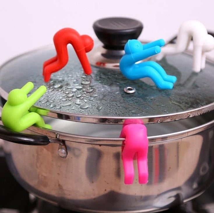 Five colorful 3D printed lid raisers holding up the lid of a pot