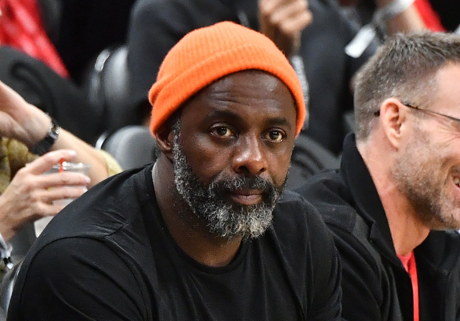 Photo of Idris Elba in a black t-shirt and orange beanie