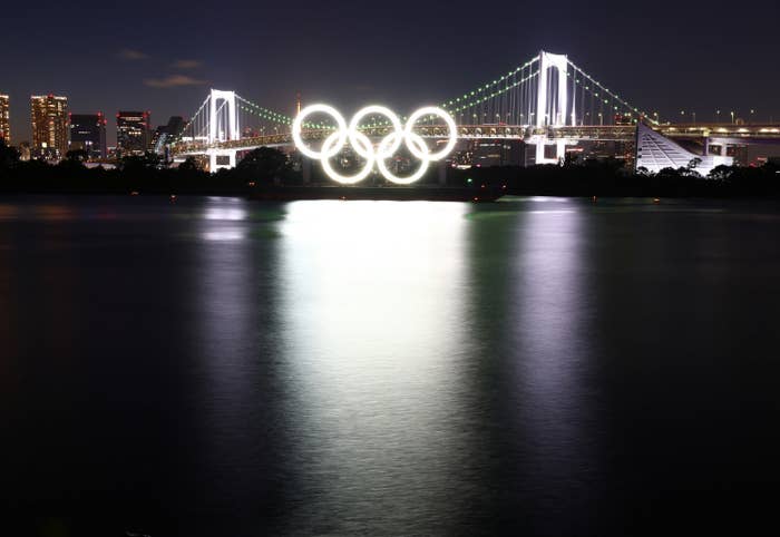 The Olympic rings lit on the side of a bridge at night