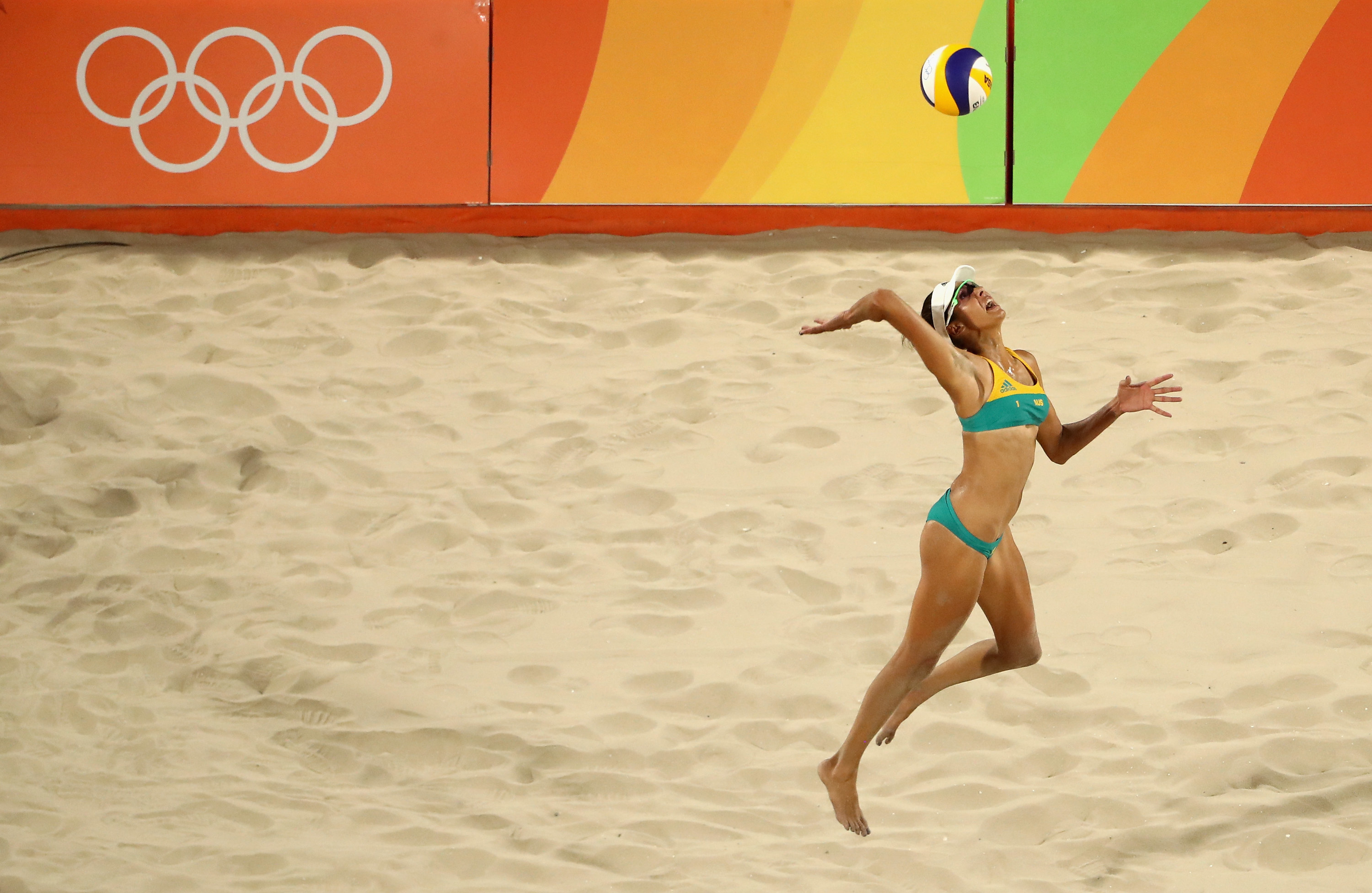 Woman serves beach volleyball