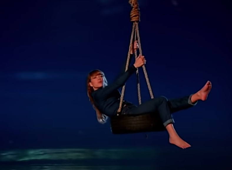 Screenshot of Mariah Carey on a tire swing over a pond