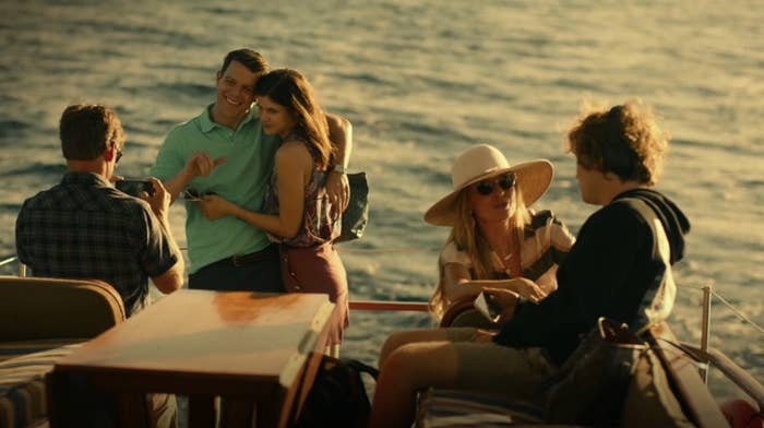 On the back of a boat at sea, Mark takes a photo of Shane and Rachel while Nicole and Quinn talk together in the foreground
