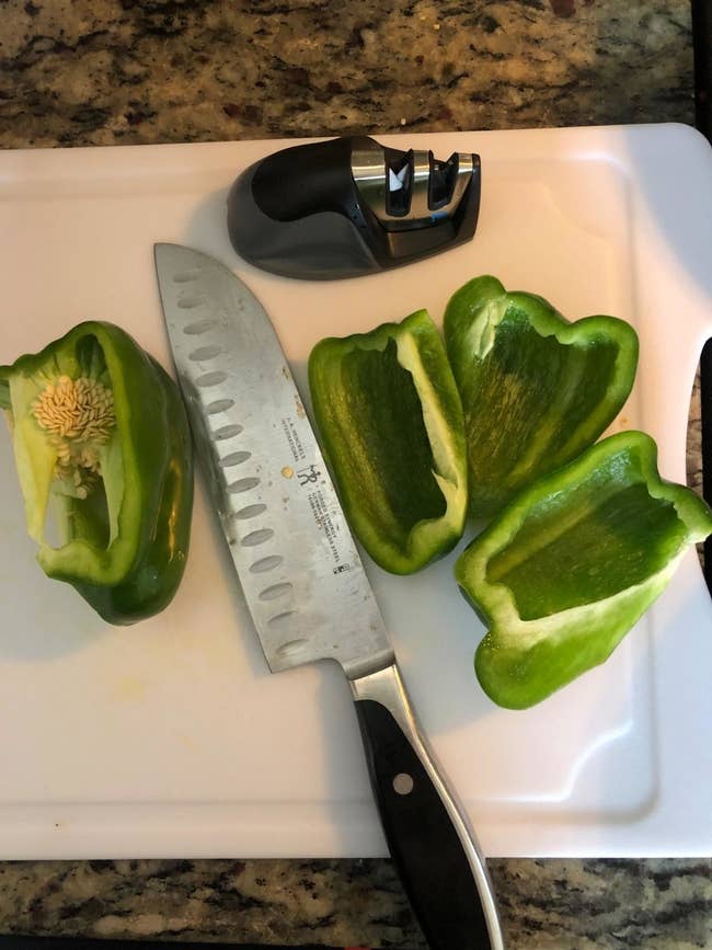 A reviewer photo of a knife next to sliced green peppers and the knife sharpener