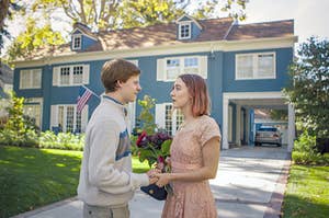 lady bird and her boyfriend standing in front of a blue house