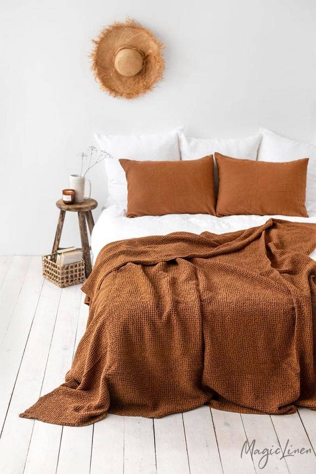 brown linen blanket on a bed with matching linen pillowcases on the pillows. The bed is unmade.