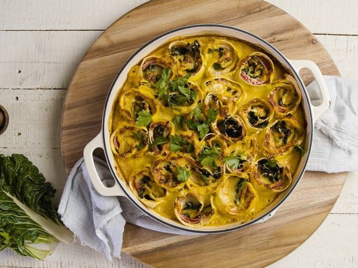 Overhead shot of a circular enamel pot with ham rosettes in pumpkin cream, garnished with parsley