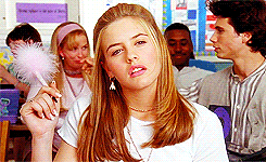 Alicia Silverstone as Claire holding a feathered pen in class