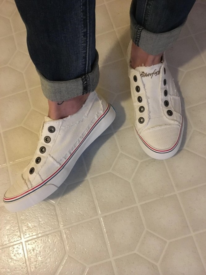 Reviewer wearing white slip on sneakers with jeans