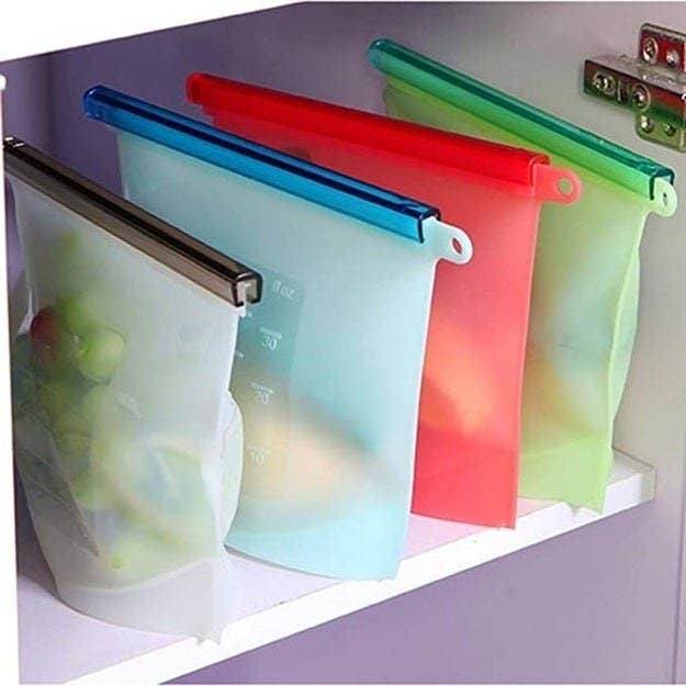 The silicone containers stored in a fridge with fruit and other leftovers in them