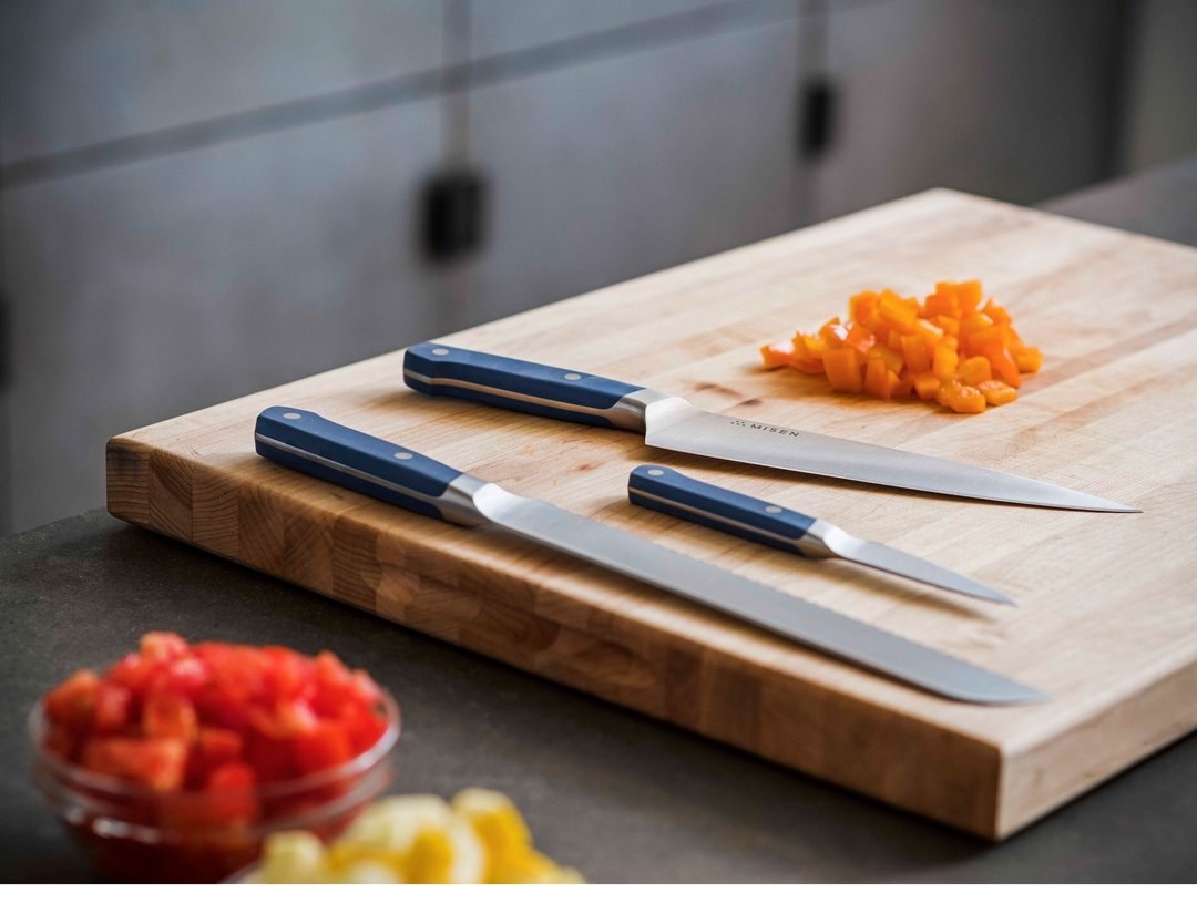 The knife set with blue handles on a cutting board
