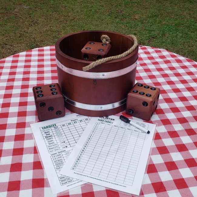 reviewer image of  the giant dice, wooden bucket and score cards on a red gingham blanket outside