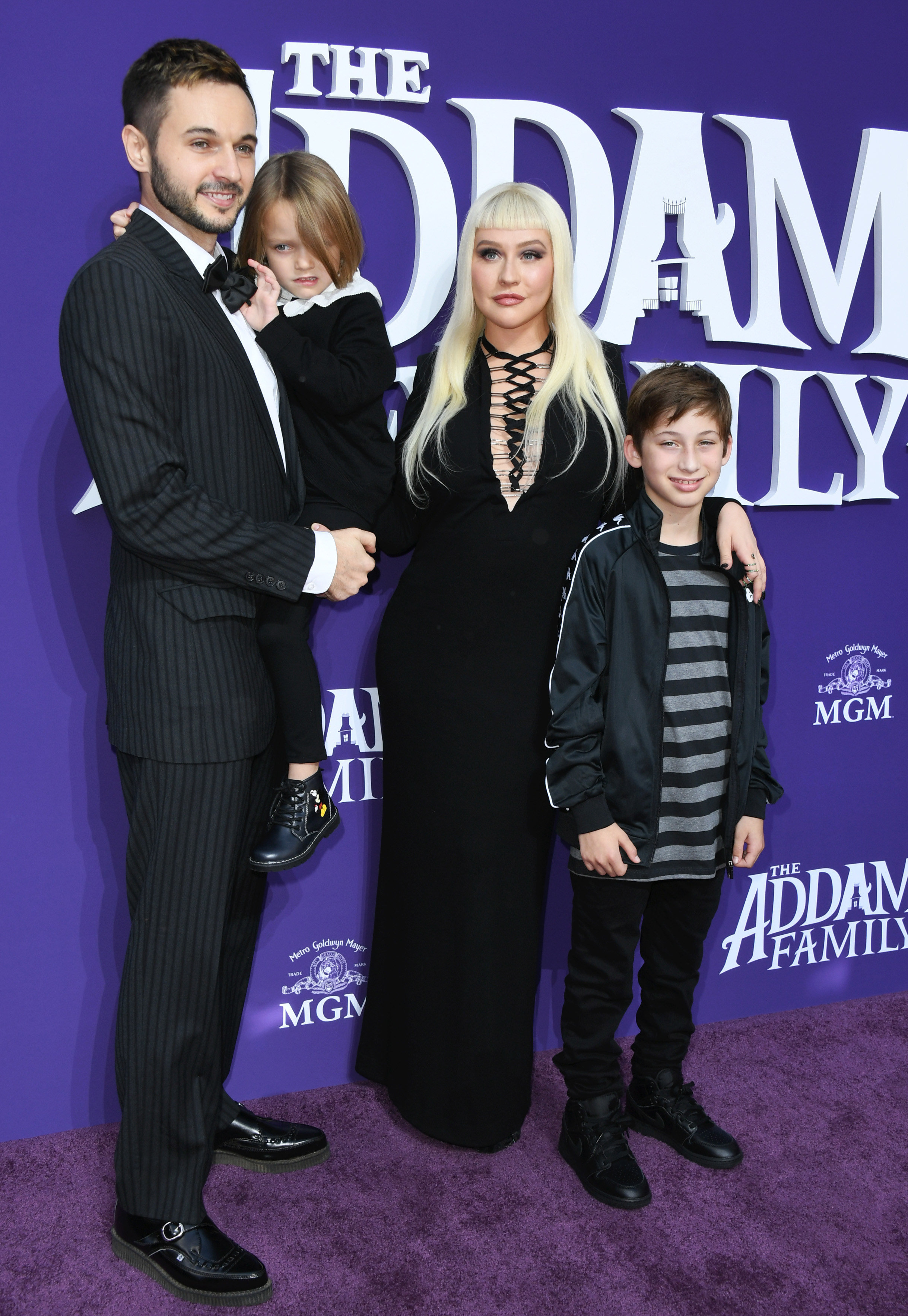with their children on a red carpet for the addams family in 2019