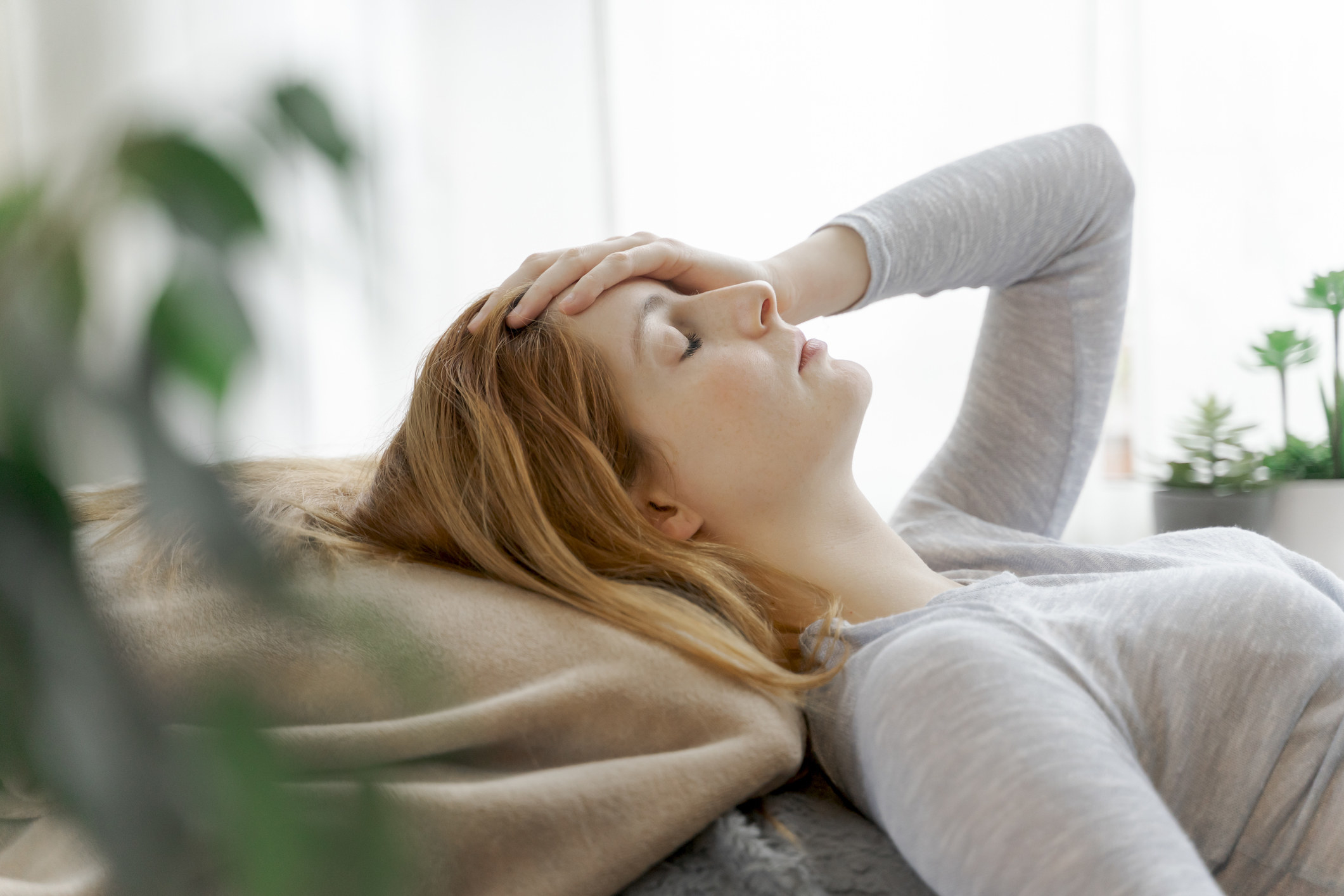 A woman lies down with her hand on her head