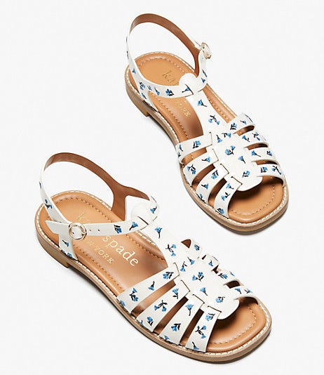 a pair of white leather sandals with a buckle ankle strap and a blue floral print