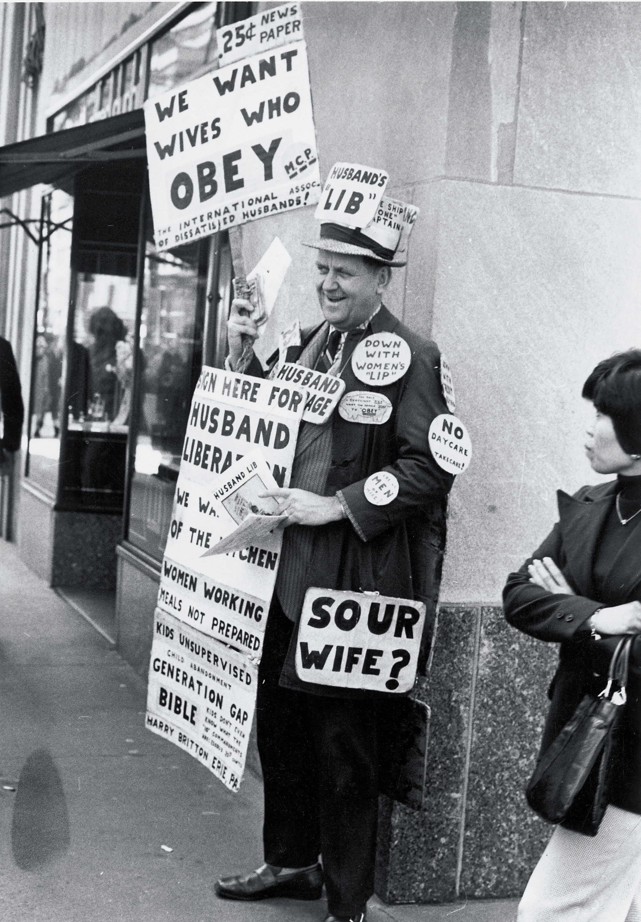 A man holding multiple signs including one that says sour wife with a question mark