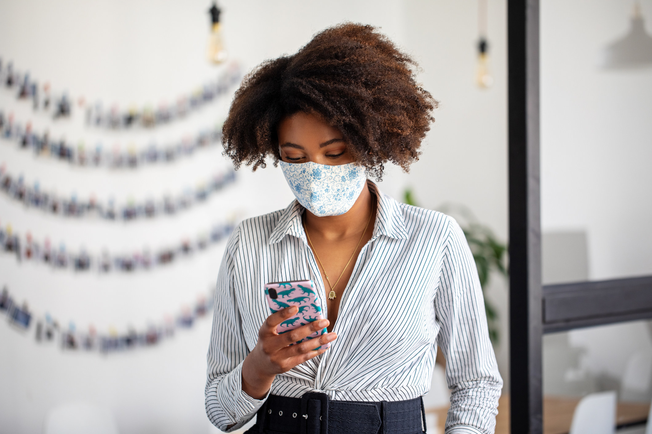 A woman with a mask on looks at her phone