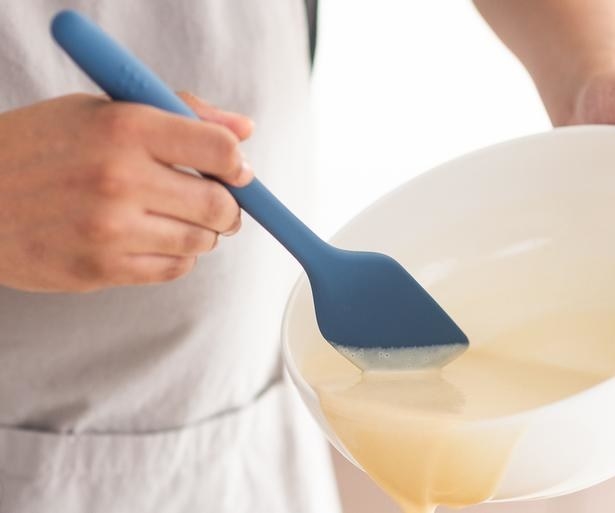 Hand spooning batter out of a bowl with the spatula