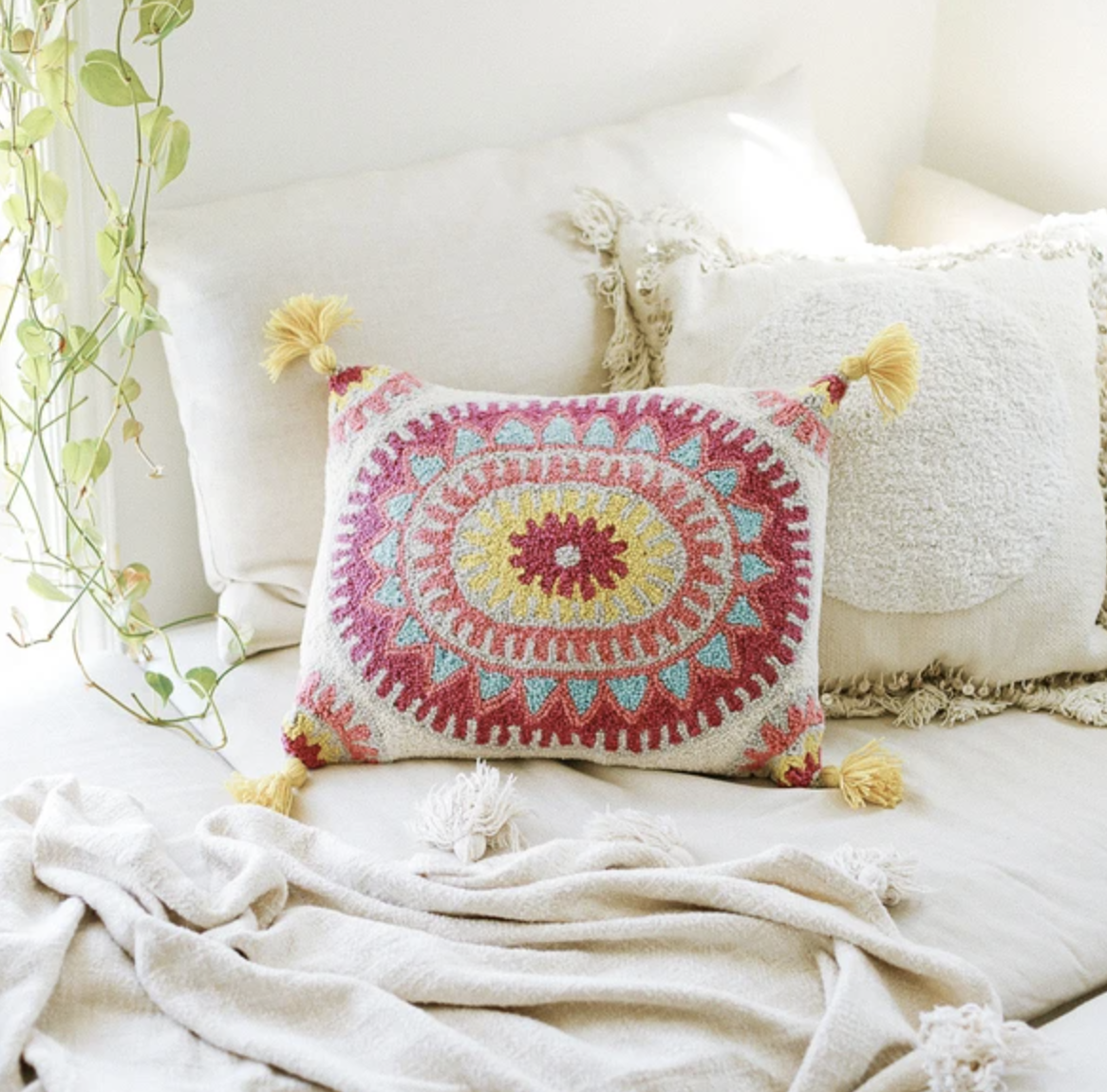 pink, white, and yellow floral-print tassel rectangle pillow on white bedding