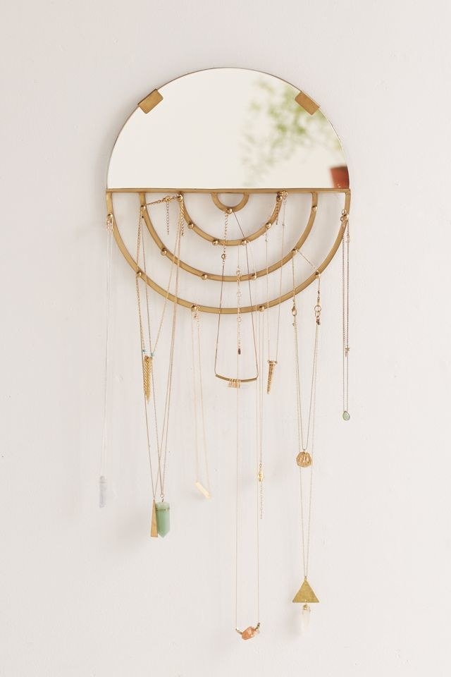 circular mirror with hanging gold jewelry on the bottom half
