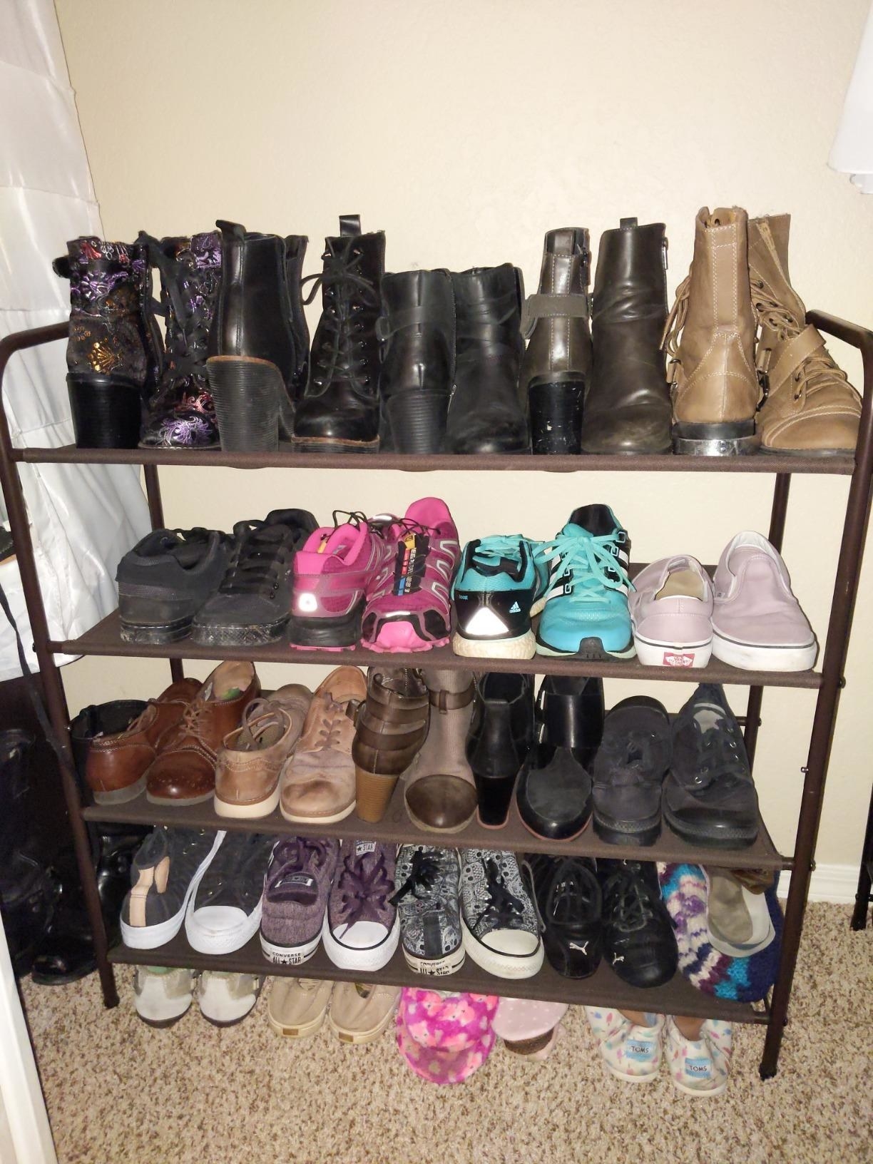Reviewer&#x27;s black four-tier shoe rack with boots and Vans sneakers