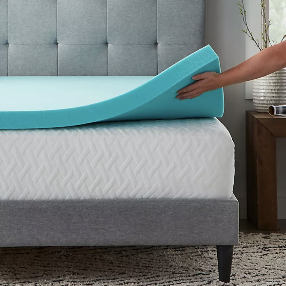 A person lifting the mattress topper