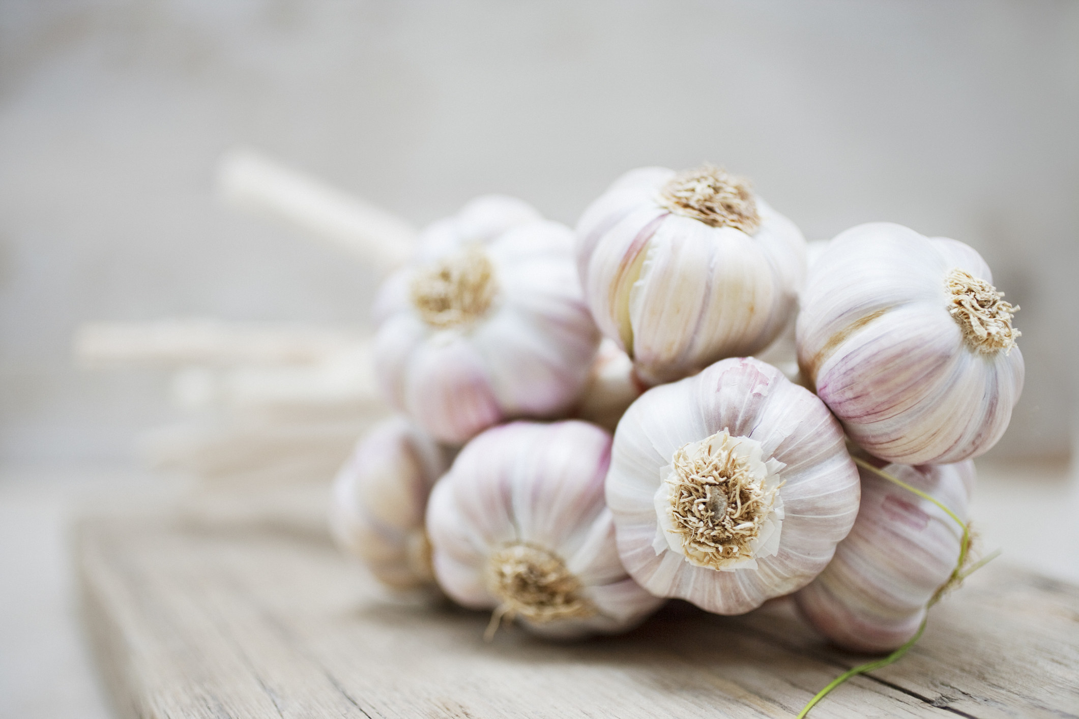 Several bulbs of garlic bundled together on a wooden board