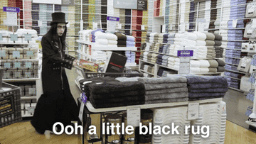 A person picking up a black rug they think is a bath mat