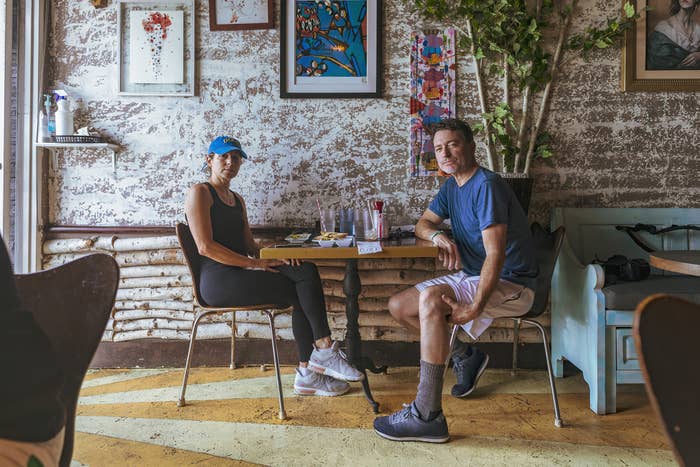 A couple in athletic clothes sit at a table with breakfast on it